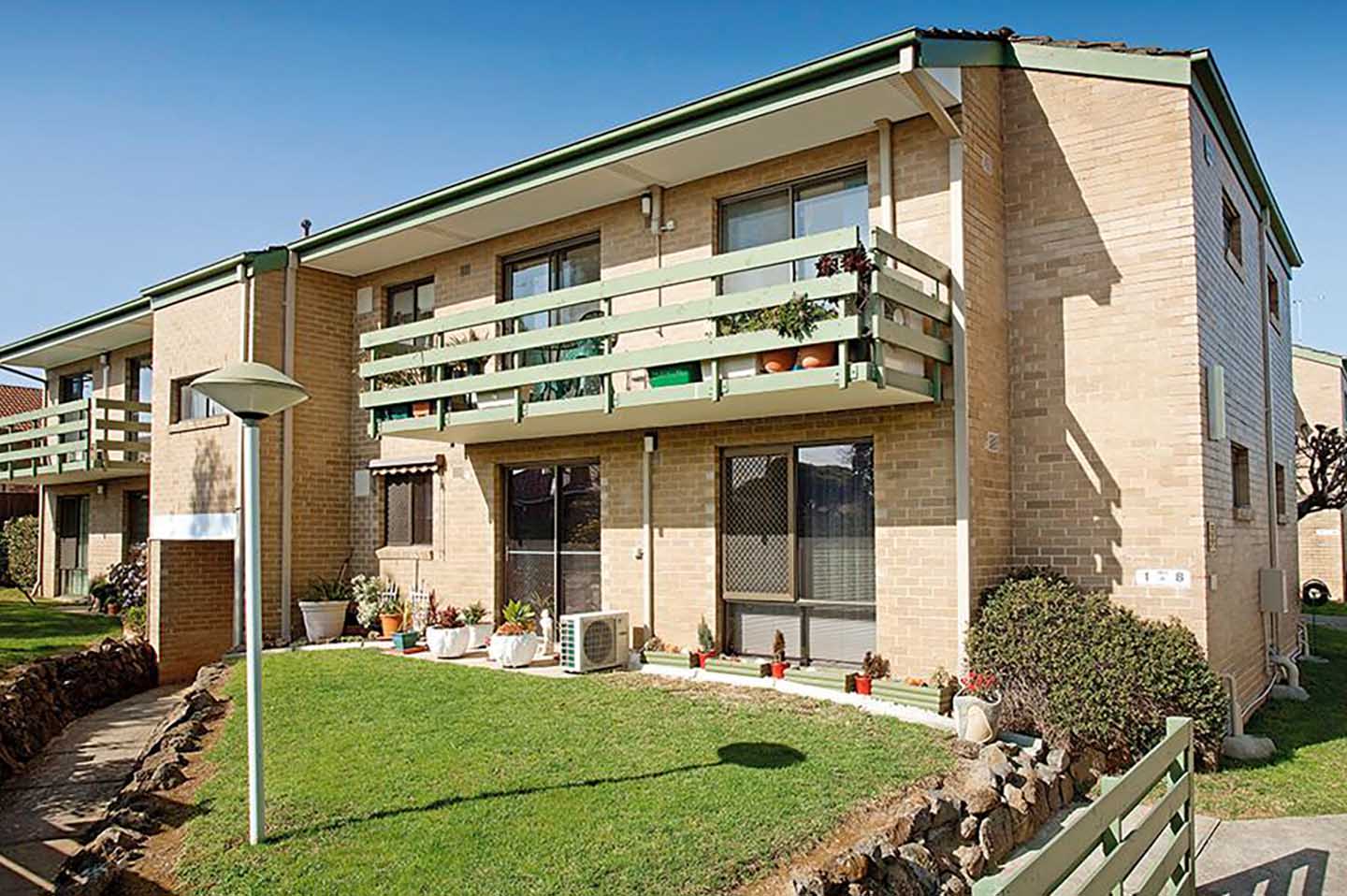 An apartment building with a balcony and a lawn, designed for retirement living.