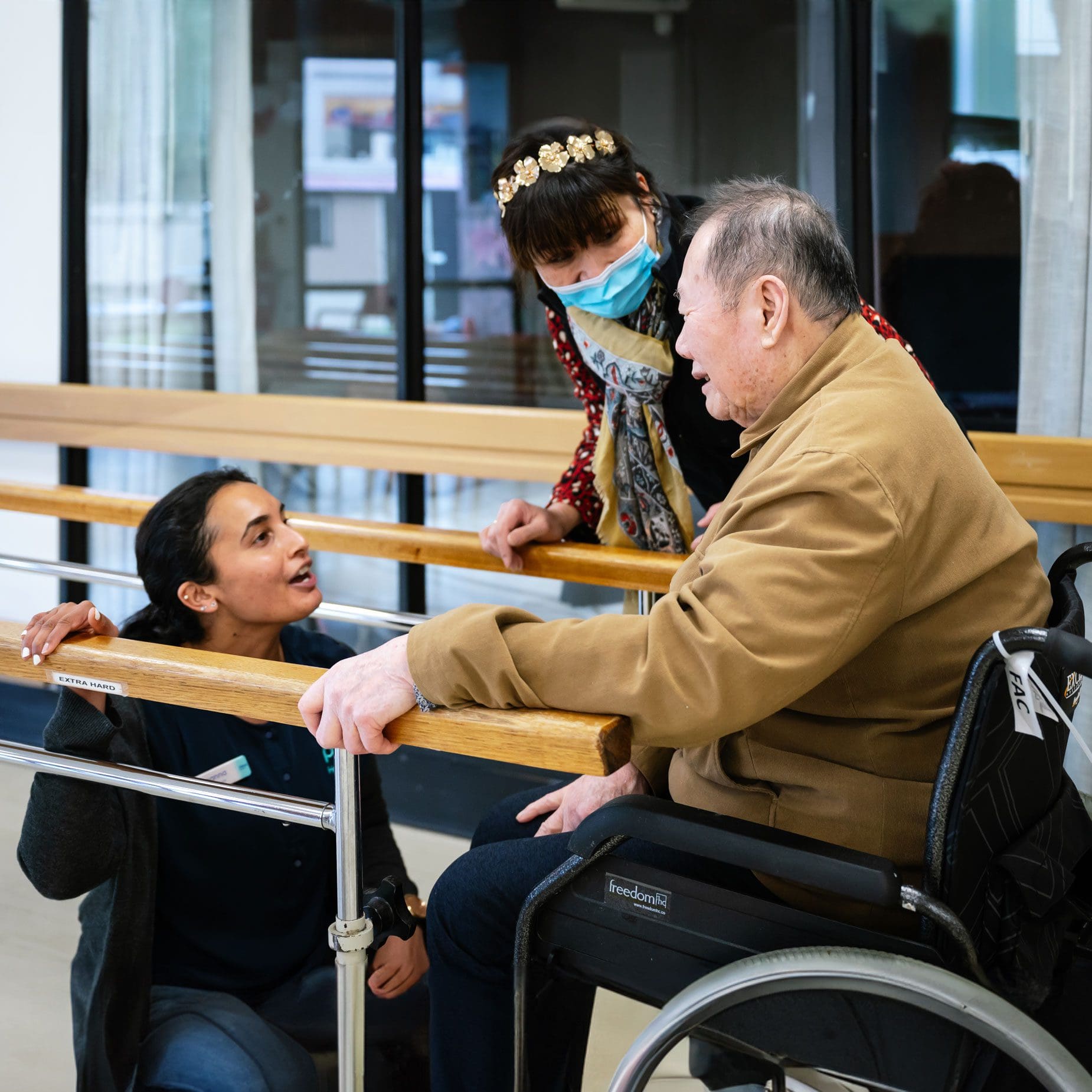 A man in a wheelchair talking to a woman in a wheelchair at an aged care home.