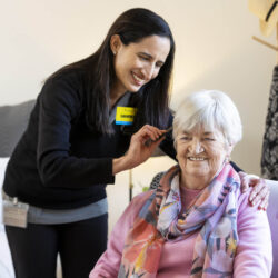 A nurse is helping an elderly woman with her ear in a residential aged care facility.