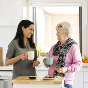 A woman talking to an older woman in a retirement village kitchen.