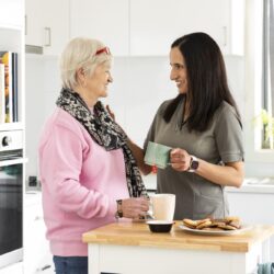 A woman talking to an older woman in a retirement village kitchen.