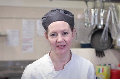 A woman wearing a chef's hat in a residential aged care kitchen.