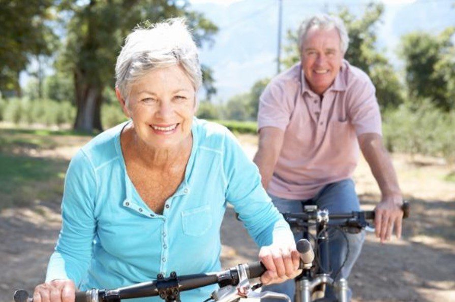 Senior couple enjoying a bicycle ride outdoors on a sunny day.