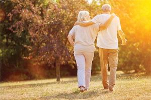 Senior couple walking together in a park at sunset.