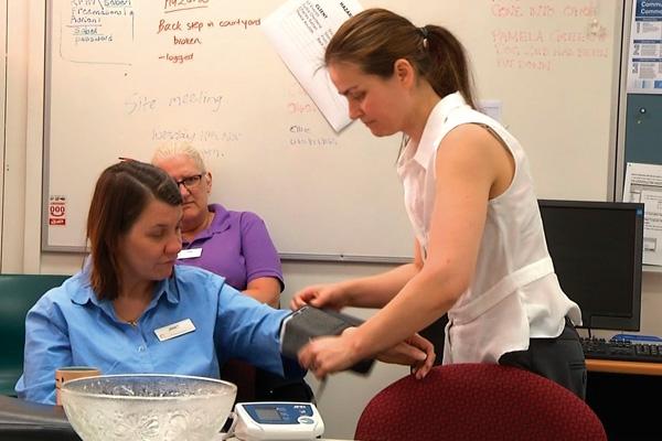 A healthcare professional is taking a patient's blood pressure in a clinical setting.