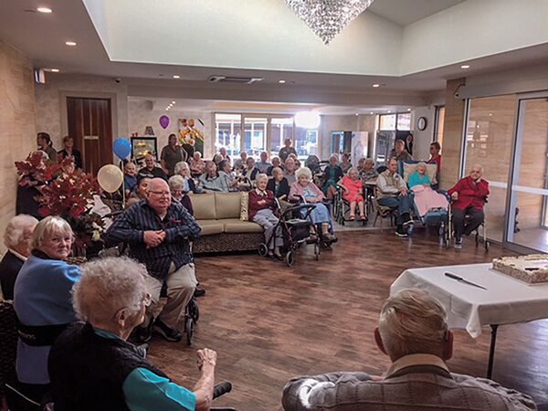 Seniors gathered in a common room for a celebratory event with balloons and cake.