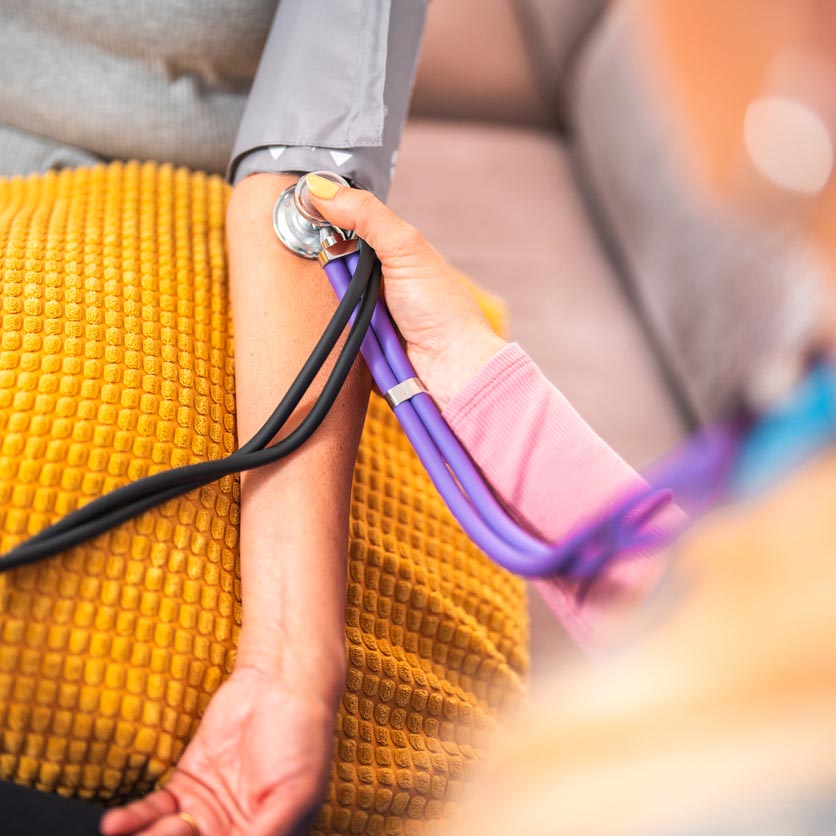 Doctor Using Sphygmomanometer And Stethoscope When Visiting A Patient At Home