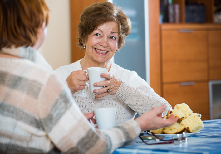 Positive female pensioners drinking coffee and chatting