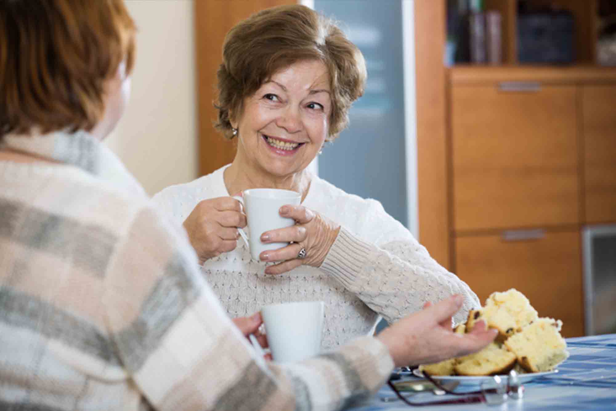 Positive female pensioners drinking coffee and chatting