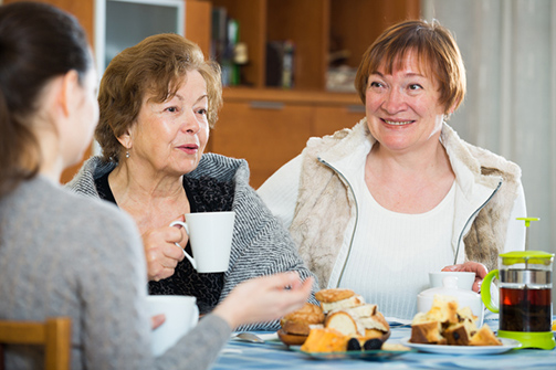 Senior women talking with girl while tea drinking