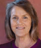 Mature woman smiling against a maroon background.