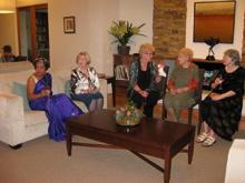 Five women sitting in a living room engaged in conversation.