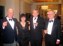 Four people in formal attire holding wine glasses at a social event.