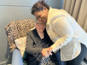 A nurse in a nursing home giving one of the female residents a hug