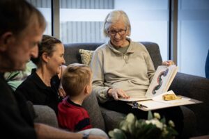 Older lady reading book to small boy. 