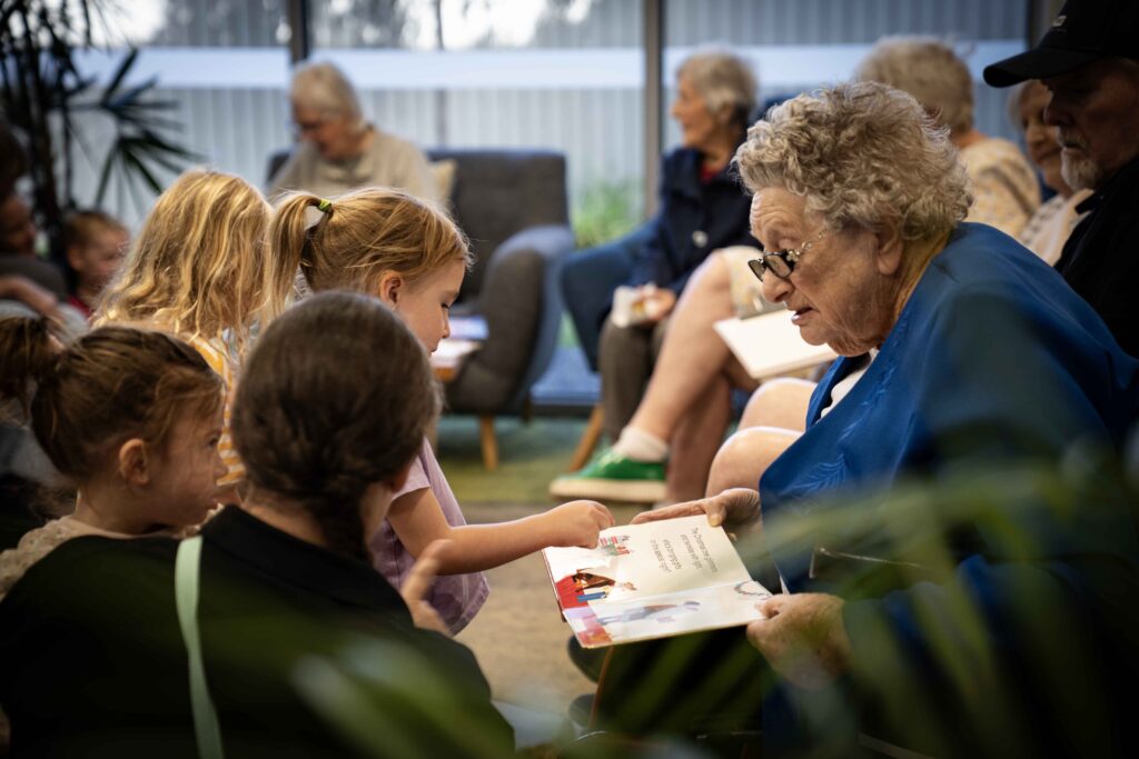 An older lady reading a story to small children