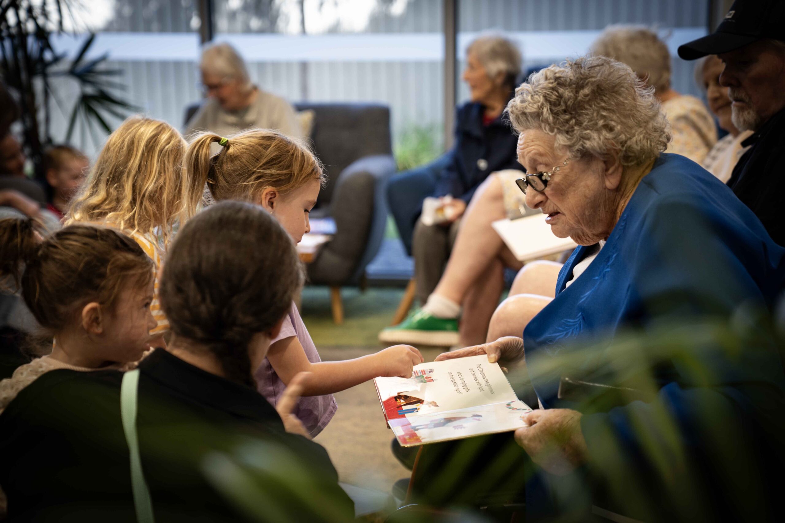 An older lady reading a story to small children
